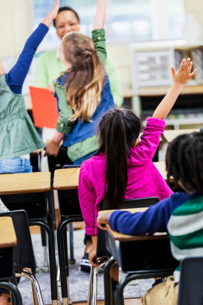 istock Asian girl raising hand in elementary school classroom 1194312917