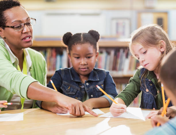 istock Teacher with children sitting at table, writing 1194314984