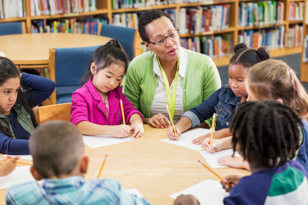 istock Teacher with children sitting at table, writing 1194314994