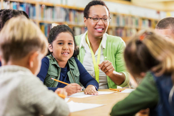 istock Hispanic girl with teacher, classmates, writing 1194315596