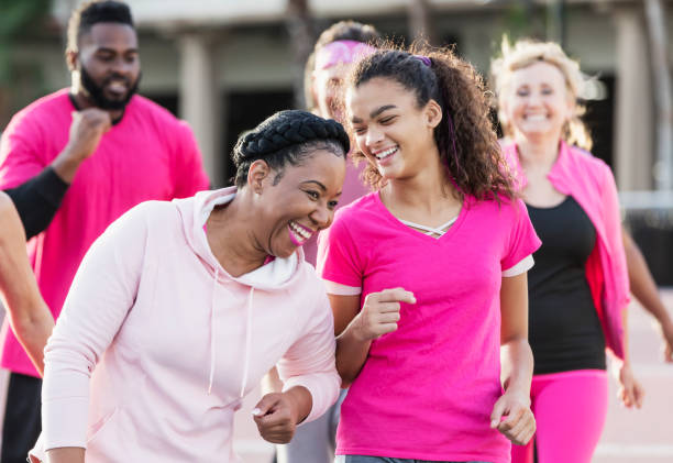 女性、10代の女の子、乳がんウォークでグループと - focus on foreground joy happiness pink ストックフォトと画像