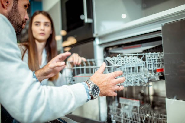 istock Young couple checking out a dishwasher machine in a kitchen appliances store 1194319940