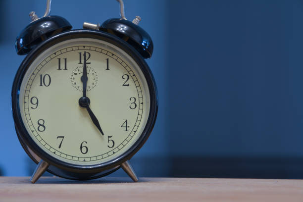 vintage and retro analogue alarm clock indicating that it's five o' clock, 5pm or 5am, on a dark blue background - 5 horas imagens e fotografias de stock