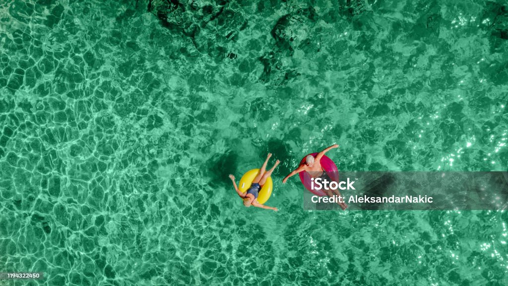 Senior par på uppblåsbara ringar i havet - Royaltyfri Flygbild Bildbanksbilder