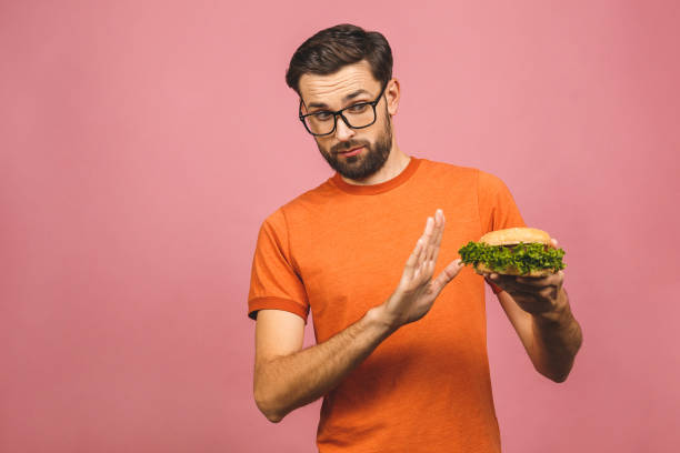 istock Handsome young man refusing unhealthy burger isolated over pink background. Diet concept. With copy space for text. 1194324016