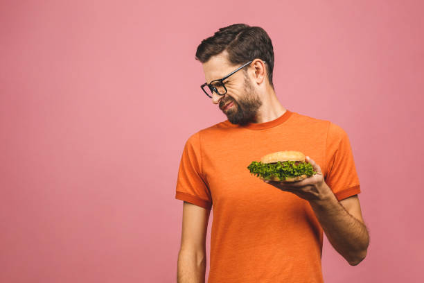 istock Handsome young man refusing unhealthy burger isolated over pink background. Diet concept. With copy space for text. 1194324043