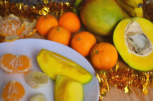 Juicy tangerines and tropical fruits on the New Year's table. On a wooden background.