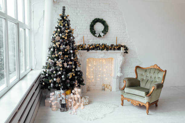 istock Beautiful holiday decorated room with Christmas tree with present boxes under it in white and blue. Large panoramic window, fireplace and armchair in classic style 1194325477
