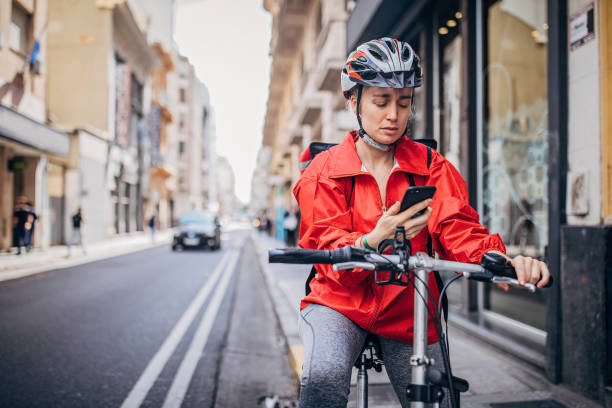young delivery woman standing on the street - bicycle messenger imagens e fotografias de stock