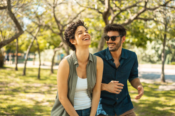 giovane coppia che si gode la giornata di sole al parco - fun walk immagine foto e immagini stock