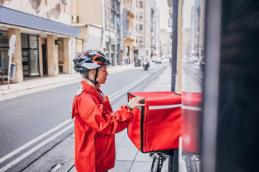 Bicycle delivery woman with road bicycle standing in front garage door