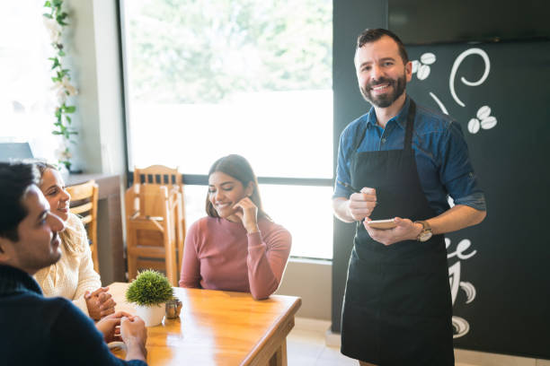 istock Smiling Waiter With Customers At Cafe 1194330414