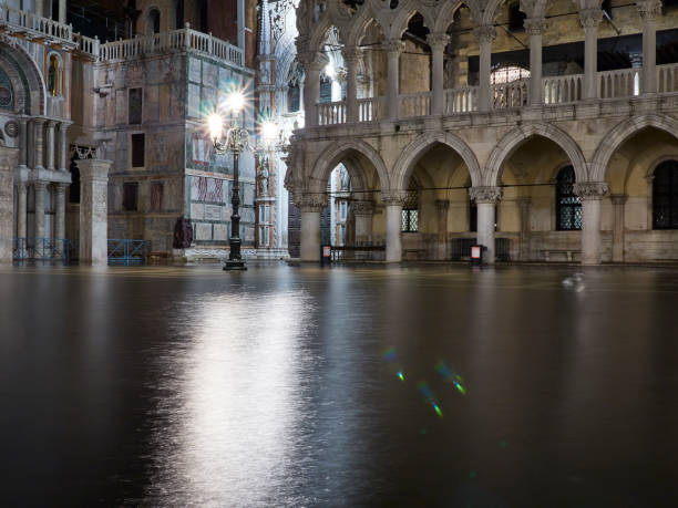 plaza san marco por la noche en venecia italy se inundó durante la marea alta de acqua alta en noviembre, consecuencia del cambio climático y el calentamiento global, el aumento de los niveles de agua - acqua alta fotografías e imágenes de stock