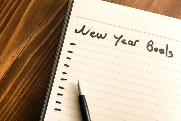 istock Conceptual,notebook on a wooden table. open diary and pen with new year goals words 1194332760