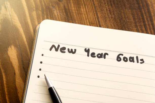 istock Conceptual,notebook on a wooden table. open diary and pen with new year goals words 1194332771