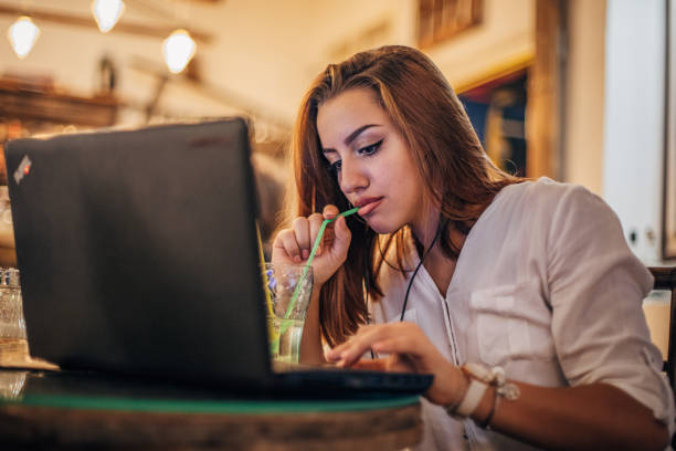 istock Young woman is having soda and using laptop 1194334128