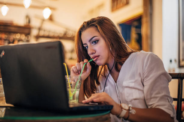 istock Young woman is drinking soda and using laptop 1194335189