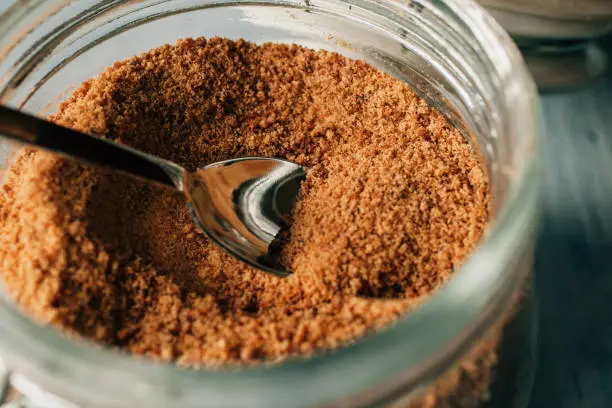 Photo of Close up view of raw cane sugar in a jar. Panela brown sugar as background. Organic and healthy food..