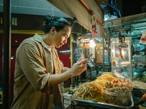 Young asian man taking a selfie with Pad Thai in Bangkok city, Khao San Road.