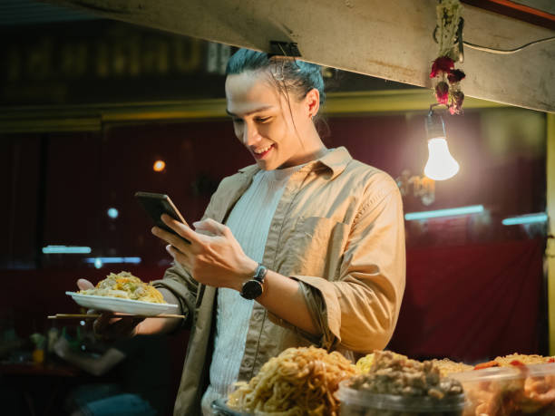 giovane che si fa un selfie con il cibo di strada pad thai a khao san road. - thailand thai culture thai cuisine pad thai foto e immagini stock