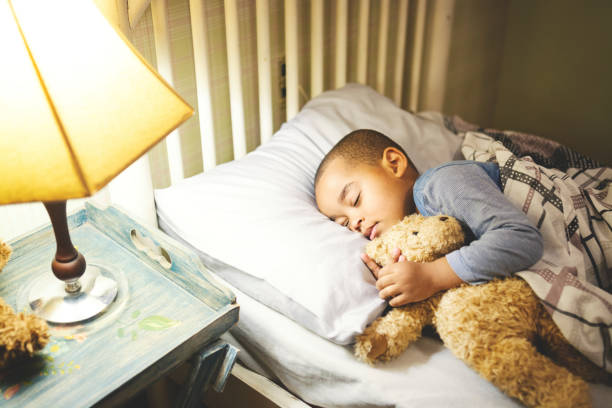 istock Cute boy sleeping on the bed embracing a teddy bear 1194337539