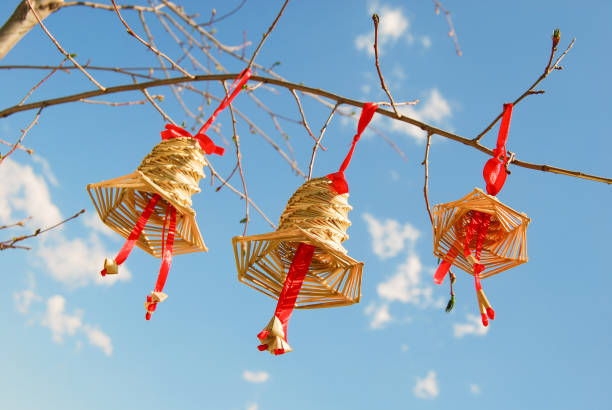 istock Three decorative straw bells hanging on tree branch in blue sunny sky. Traditional amulets welcoming springtime 1194338263