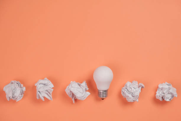 istock Creativity inspiration, great business idea concept with white light bulb and paper crumpled ball on orange background. Flat lay, top view, copy space 1194338329