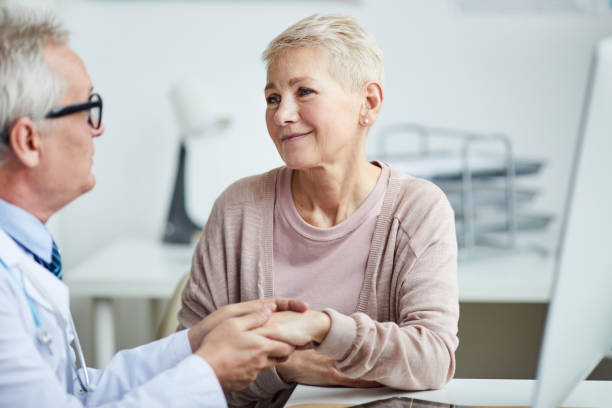 istock Professional male practitioner sitting at table and touching hands of female patient while supporting her 1194338421