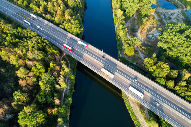 luftaufnahme von lastwagen und autos auf autobahnbrücke über fluss - commercial land vehicle stock-fotos und bilder