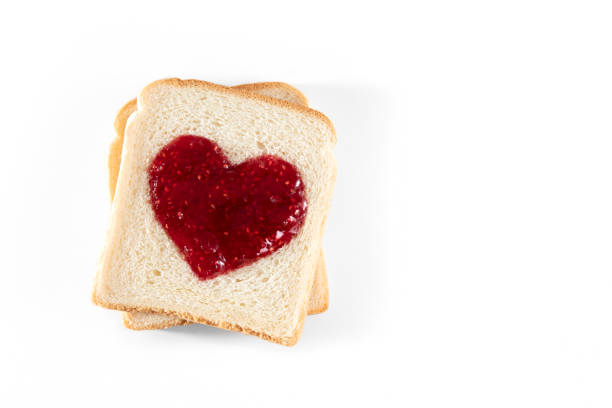 slice of heart shaped bread and raspberry jam on white background - raspberry heart shape gelatin dessert valentines day imagens e fotografias de stock