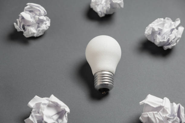 istock new idea concept with crumpled office paper and white light bulb on grey background. Creative solution during brainstorming session concept. Flat lay, top view, copy space 1194342805