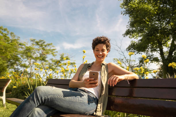 istock Young woman using mobile phone in the park 1194343869