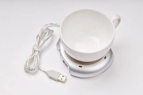 electronic usb hub and heater for cup coffee or tea at office. digital usb warmer device on grey background.