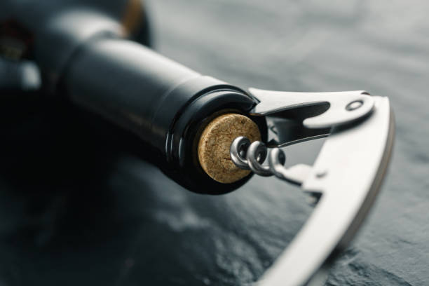 Stainless  wine corkscrew in a cork of wine bottle neck on a black slate background Stainless  wine corkscrew in a cork of wine bottle neck on a black rocky slate background uncork wine stock pictures, royalty-free photos & images