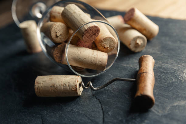 sacacorchos de vino y copa de vino llena de corchos sobre un fondo de pizarra negra - cork wine corkscrew old fotografías e imágenes de stock