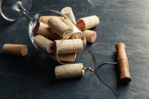 istock Wine corkscrew and wine glass full of corks on a black slate background 1194347594
