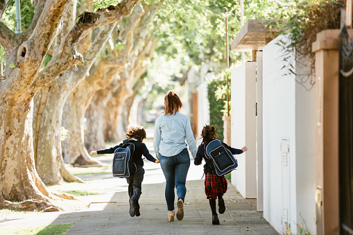 Mother running with son and daughter to school in the morning