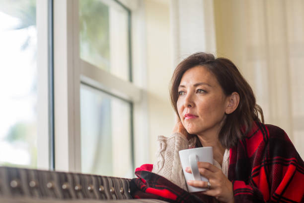 istock Mature woman looking out the window feeling sad. 1194354438