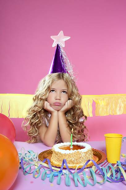 entediado pequena menina loira em festa com bolo de aniversário com velas - streamer ribbon curly hair party - fotografias e filmes do acervo