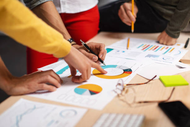 What do the charts say? Close-up shot of a group of colleagues going through paperwork together in the office travel agency stock pictures, royalty-free photos & images