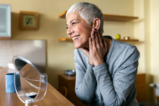 Mature woman aging. Impressed with the results of her anti-aging cream Beautiful senior woman checking her face skin and looking for blemishes. Portrait of mature woman massaging her face while checking wrinkled eyes in the mirror. Wrinkled lady with grey hair checking wrinkles around eyes, aging process. anti aging stock pictures, royalty-free photos & images