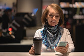 Woman at a cafe looking at social media on her cell phone