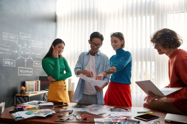 istock We need a new website. Group of four young designers discussing new project and sharing ideas while having a meeting in the modern office. Web design concept. Teamwork 1194380237