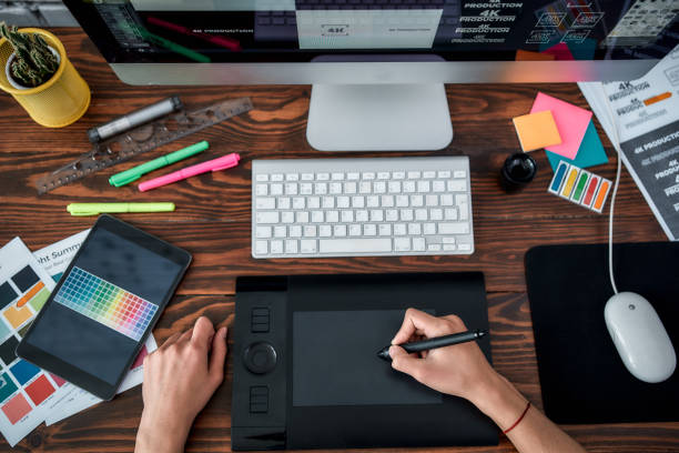 Design tools. Top view of a designer using graphic tablet and working with computer while sitting at his workplace in the office. Top view of a workplace with graphic tablet, keyboard and computer. Top view of a designer using graphic tablet and working with computer while sitting at his workplace in the office. Top view of a workplace with graphic tablet, keyboard and computer. graphic design careers stock pictures, royalty-free photos & images