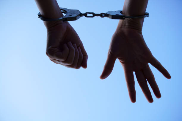 istock silhouette of prisoner hands against blue sky 1194384695