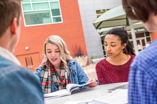 Two Female Students Studying Together Outdoors in Winter on University Campus College University Students spending time outdoors and bonding together community college stock pictures, royalty-free photos & images