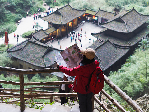 Asian tourist woman looking to the map at Three Natural Bridges National Geopark (Tian Keng San Qiao) a UNESCO world heritage of Wulong in Chongqing, China.