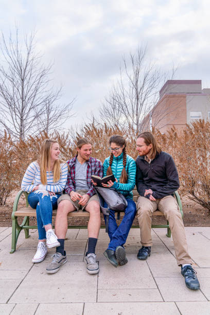 istock Group of Students Sitting on a Bench Talking Together Outdoors in Winter on University Campus 1194389296