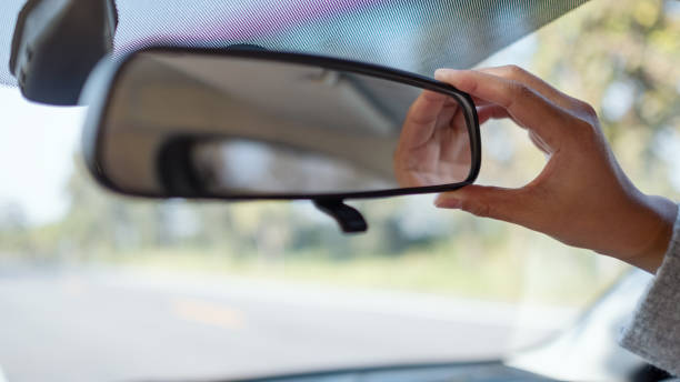 istock woman adjusting a rear view mirror while driving car 1194390186