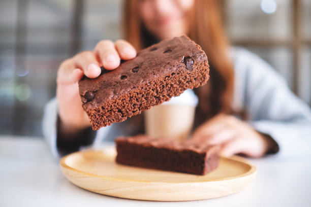 ブラウニーケーキを持ち、見せる美しい女性 - bread bakery women cake ストックフォトと画像